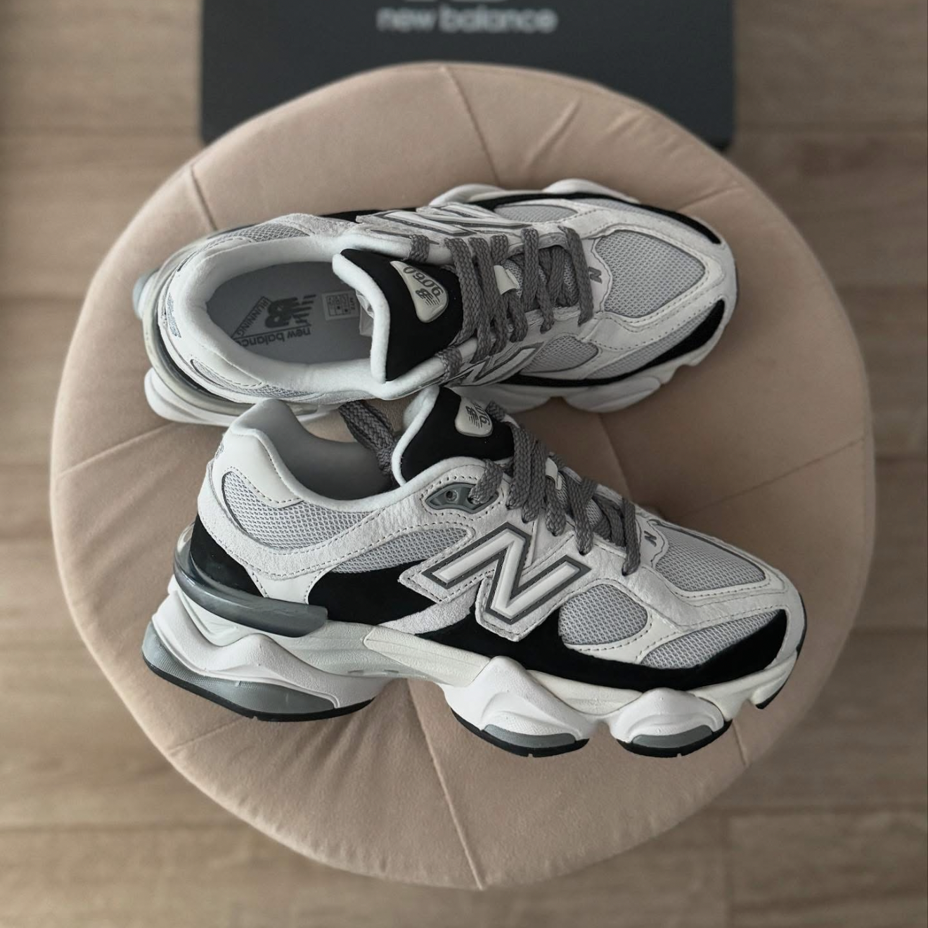 Pair of New Balance sneakers on a beige cushion with a blurred background